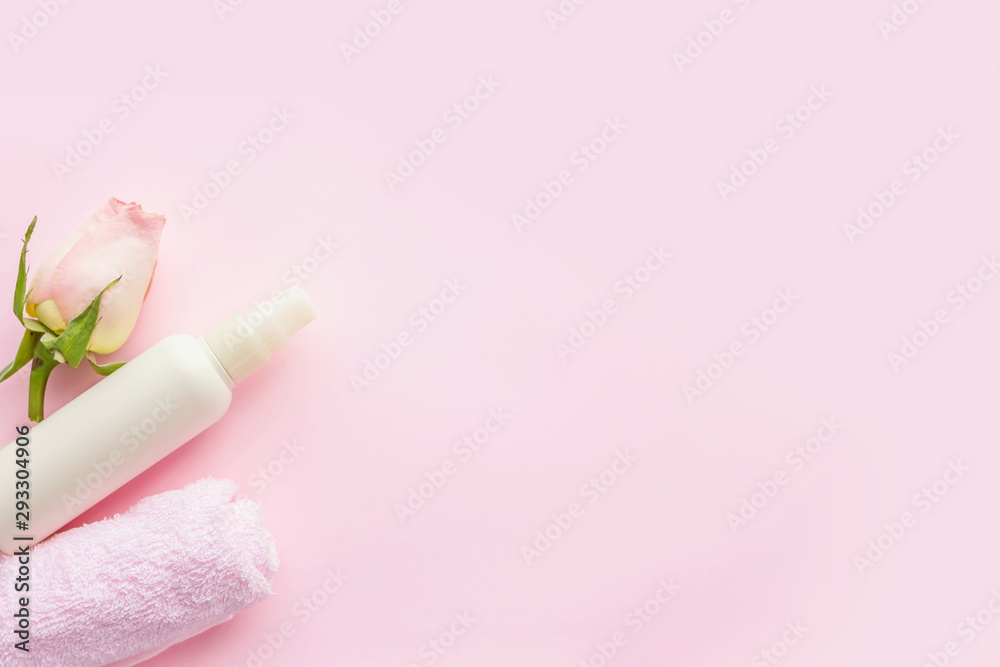 White cosmetics bottle, rose and towel on pink background. Concept of natural spa cosmetics. Flat lay, top view, copy space . White cosmetics bottle, rose and towel on pink background. Concept of natural spa cosmetics. Flat lay, top view, copy space .