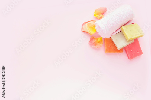 Soap, rose petals and towel on pink background. Concept of natural spa cosmetics. Flat lay, top view, copy space . © Lyubov