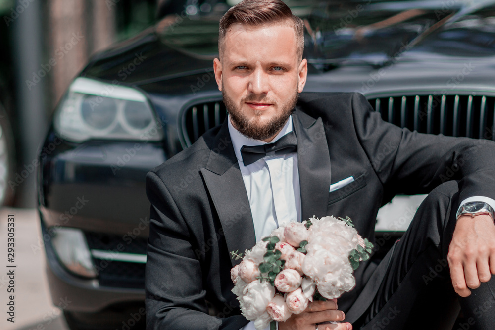beautiful groom sitting near the wedding car. beautiful groom sitting near the wedding car.