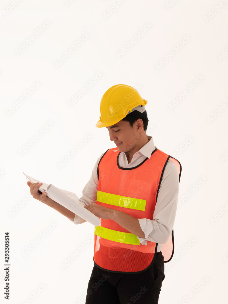 A young Asian engineer wearing yellow security helmet and safeguard jacket is examining the work with the white background. A young Asian engineer wearing yellow security helmet and safeguard jacket is examining the work with the white background.
