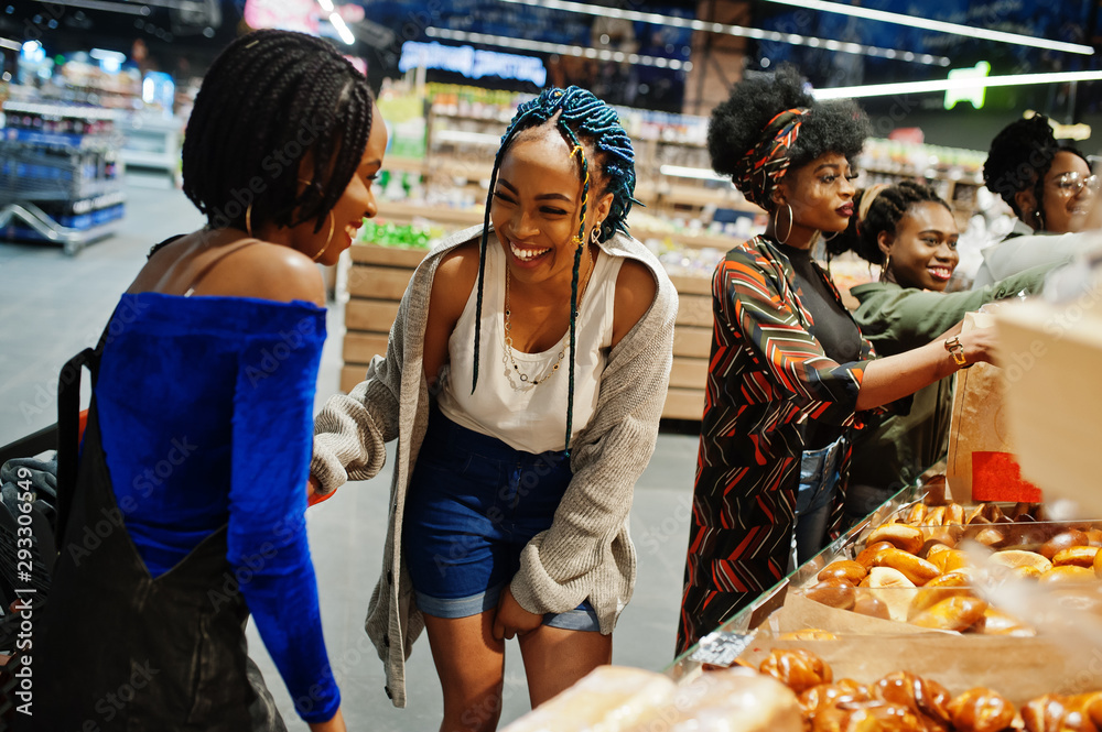 Group of african womans with shopping carts near baked products at a supermarket. Group of african womans with shopping carts near baked products at a supermarket.