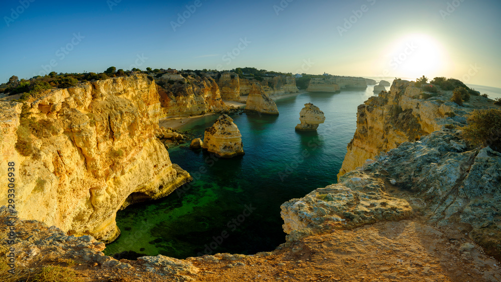 Obraz premium Faro, Portugal - September 18, 2019: Blue hour and sunrise along the Algarve coast towards Faro from the cliffs above Praia da Marinha, Portugal