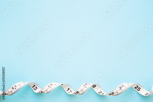 Measure tape on pastel blue background. Mock up for body slimming, weight loss or dressmaker's offer or other ideas. Empty place for text, quote or sayings.