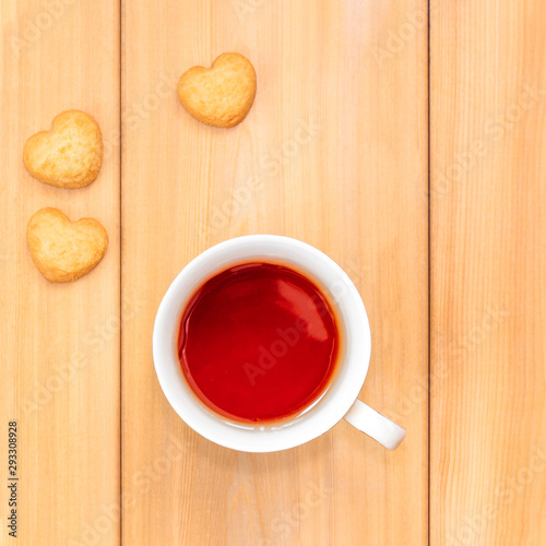 Cup of tea and sweet cookies in shape of heart on wooden background. Good morning concept.