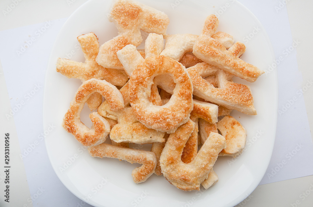 Puffs with sugar in the form of letters of the English alphabet on a plate