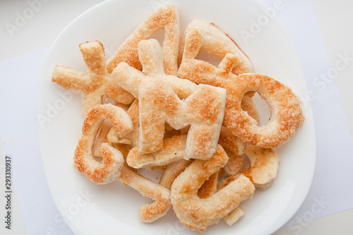 Puffs with sugar in the form of letters of the English alphabet on a plate