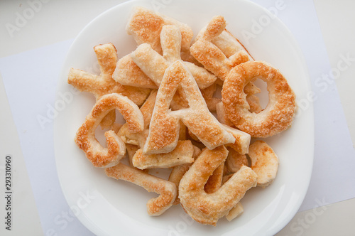 Puffs with sugar in the form of letters of the English alphabet on a plate