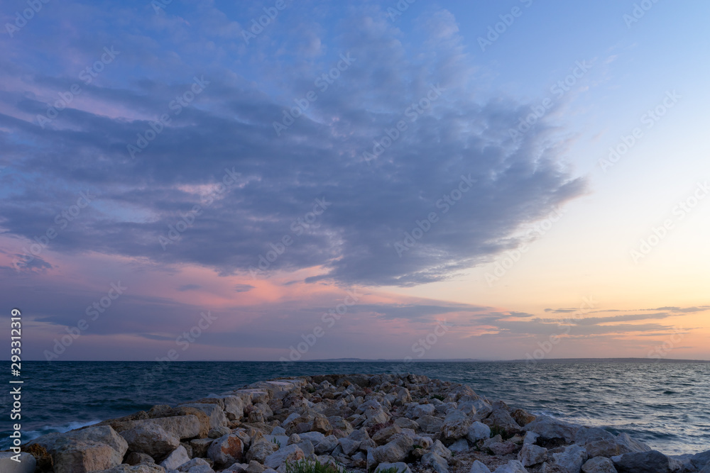 Atardecer desde espigón del mar mediterráneo con gran nube en el cielo. Santa Pola, Alicante, España