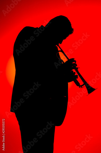 Canvas Print Silhouette of a jazz musician  playing trumpet, isolated in red background