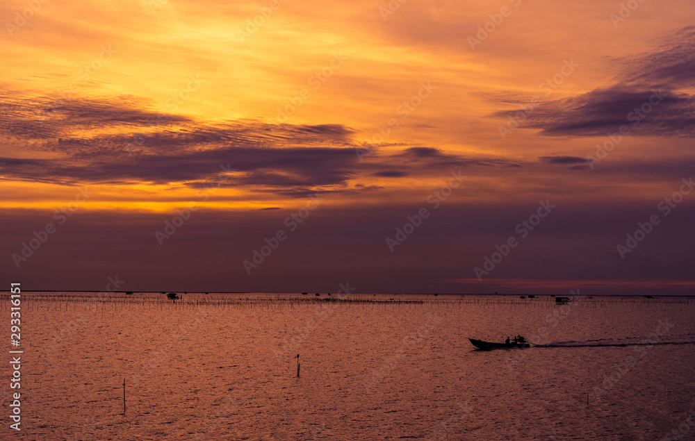 Beautiful dramatic sunset sky. Dark and orange sunset sky and clouds. Nature background for tranquil and peaceful concept. Tropical sea at dusk. Long tail boat sailing by fisherman. Beauty in nature.