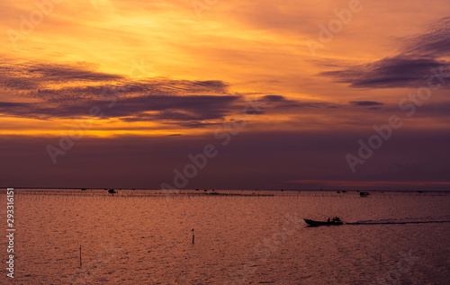 Beautiful dramatic sunset sky. Dark and orange sunset sky and clouds. Nature background for tranquil and peaceful concept. Tropical sea at dusk. Long tail boat sailing by fisherman. Beauty in nature.