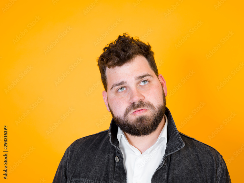 Fototapeta premium one cool man with black beard and black hair is posing in front of orange background