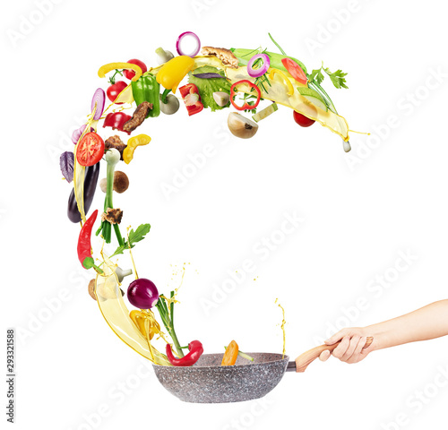 Cooking concept. Vegetables are flying out of the pan isolated on white background. Healthy food. photo