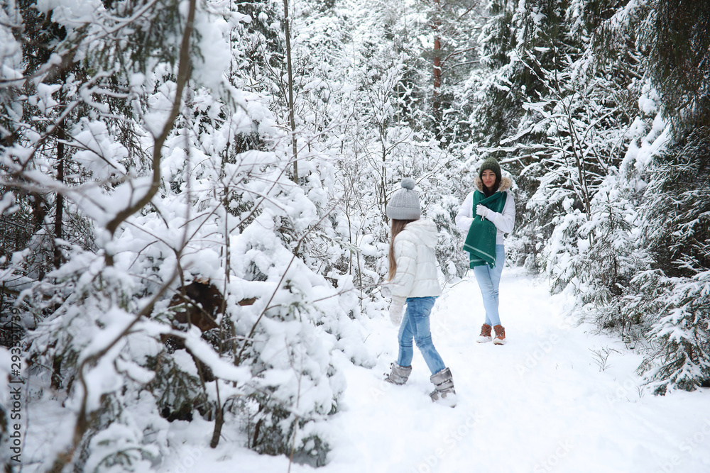 Young family for a walk. Mom and daughter are walking in a winter park.