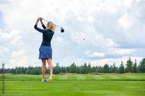Portrait of a beautiful woman playing golf on a green field outdoors background. In full growth. Back vie. The concept of golf, the pursuit of excellence, personal excellence, royal sport.