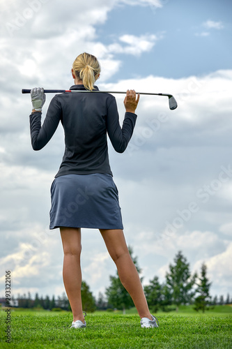 Portrait of a beautiful woman playing golf on a green field outdoors background. In full growth. Back vie. The concept of golf, the pursuit of excellence, personal excellence, royal sport.
