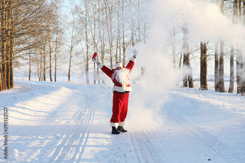 Santa in the winter field. Santa magical fog is walking along the field. Santa on Christmas Eve is carrying presents to children in a red bag.