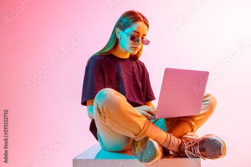 Modern Girl with laptop, tablet computer. Free creativity. A young blogger makes a Home office. Colored Neon light and background.