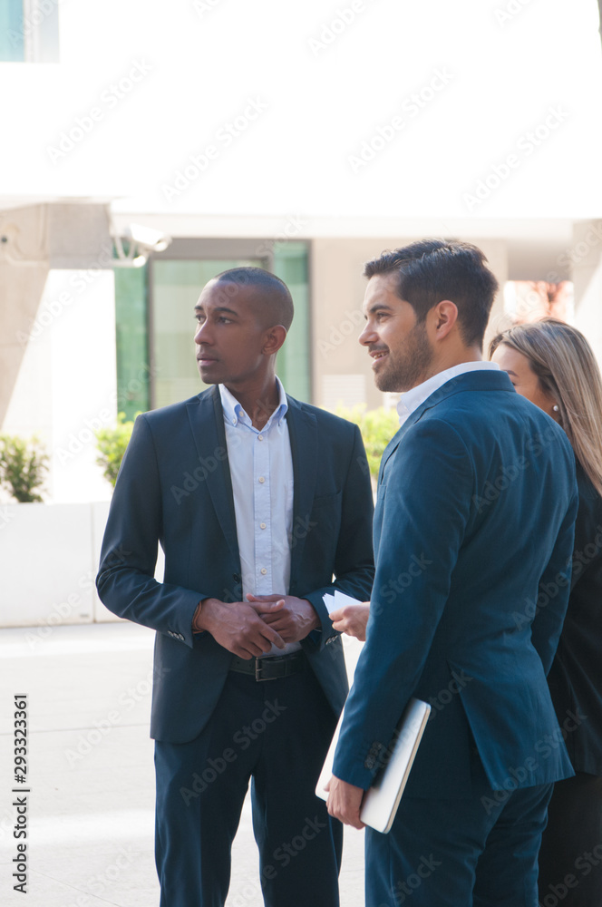 Fototapeta premium Confident business team waiting company partners outside. Business men and woman standing near office building and looking into distance. Meeting outside concept