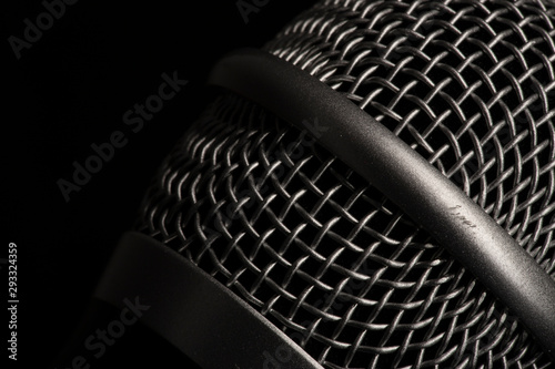 Close-up black microphone head isolated on black background.