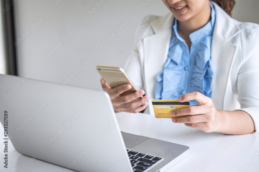 Young woman consumer holding smartphone, credit card and typing on laptop for online shopping and payment make a purchase on the Internet, Online payment, networking and buy product technology Young woman consumer holding smartphone, credit card and typing on laptop for online shopping and payment make a purchase on the Internet, Online payment, networking and buy product technology