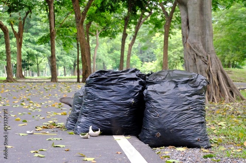 A group of trash bags on the street ground floor at the park ,on the road and green nature background for an environmental cleaning concept