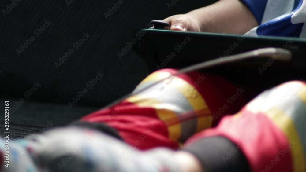 Pan reveal young boy toddler with controller playing electronic TV video games sitting on sofa wearing fireman pants socks jersey New generation technology hand–eye coordination skills gaming adiction