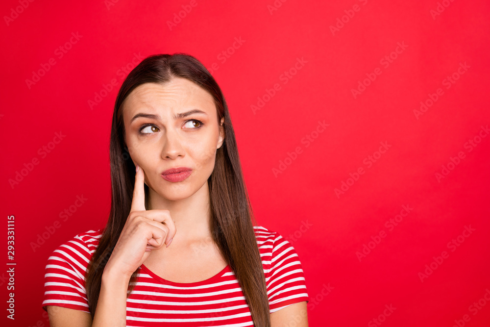 Close up photo of charming attractive thinking girl wearing red striped t-shirt pondering over something puzzling while isolated over red background Close up photo of charming attractive thinking girl wearing red striped t-shirt pondering over something puzzling while isolated over red background