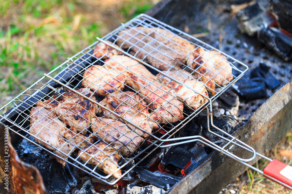 Grilled meat in barbecue with flames and coals.