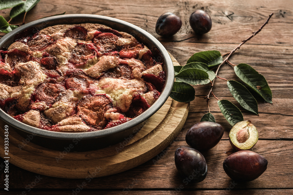 Plum cake caramelized and plums on wood backgraund. Round tart decorated by fruits and leaves Plum cake caramelized and plums on wood backgraund. Round tart decorated by fruits and leaves