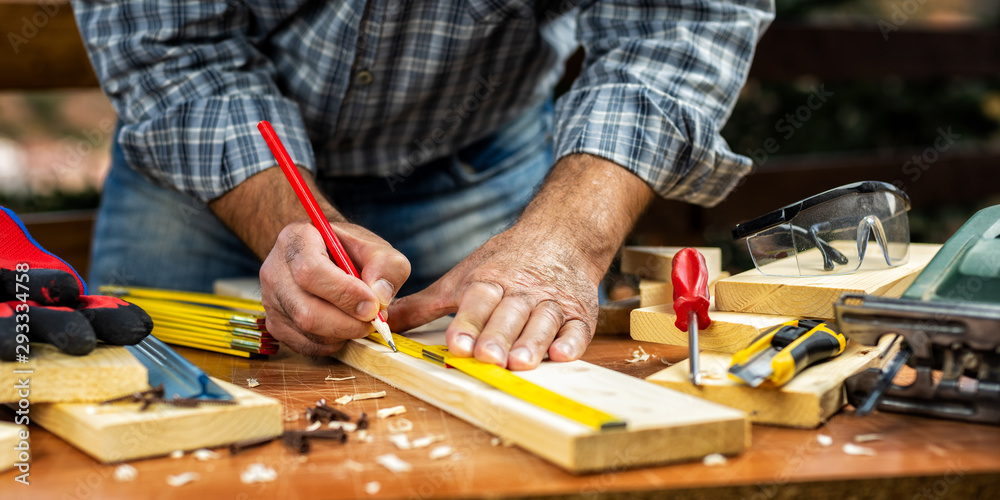 Adult craftsman carpenter with the meter measuring a wooden table. Housework do it yourself. Stock photography. Adult craftsman carpenter with the meter measuring a wooden table. Housework do it yourself. Stock photography.
