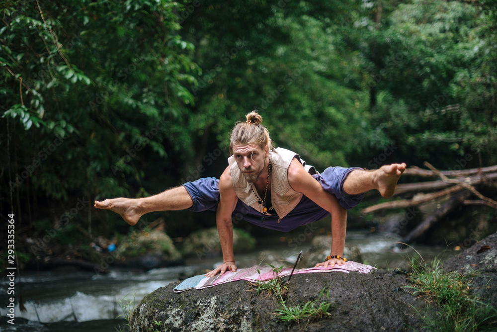 Yoga practice and meditation in nature. Man practicing near river Yoga practice and meditation in nature. Man practicing near river