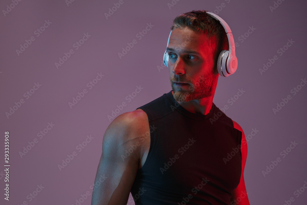 Naklejka premium Sports man posing isolated listening music with headphones.