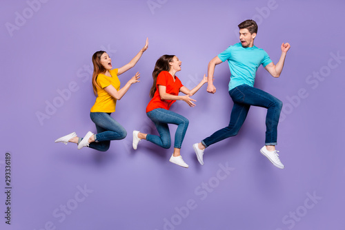 Full size body side profile view photo of one unhappy shocked guy running away from two obsessive addicted ladies isolated violet background