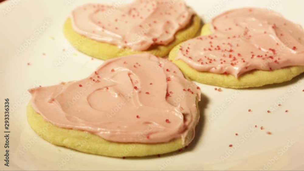 Clip of red sugar sprinkles being put on pink heart valentines days cookies Clip of red sugar sprinkles being put on pink heart valentines days cookies