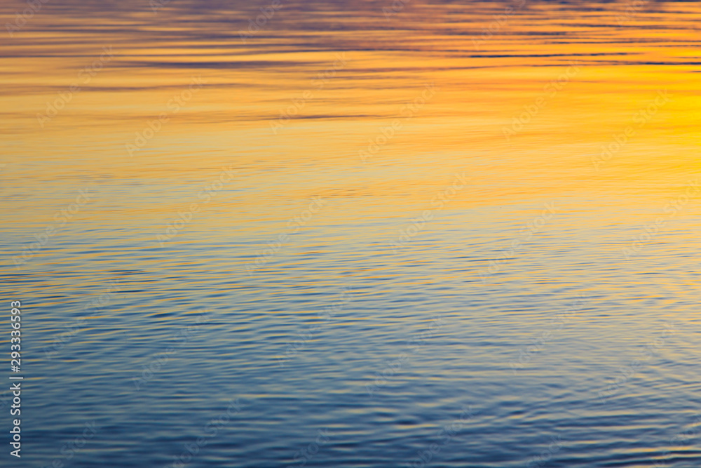Clear water texture in blue and orange. Background of the ocean and the sea backlit by the sun. Soft waves. Natural water Clear water texture in blue and orange. Background of the ocean and the sea backlit by the sun. Soft waves. Natural water