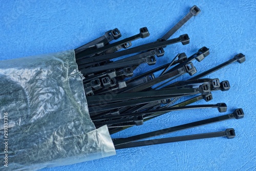 set of black cable ties in gray cellophane packaging on a blue table photo