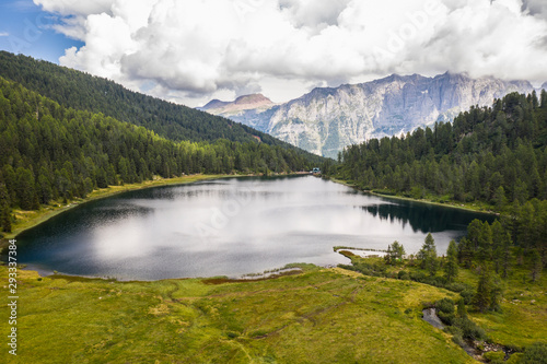 aerial view of a mountain lake in the Dolomites with refuge among firs and mountains