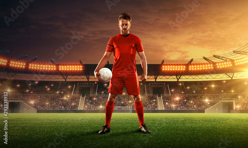 Soccer player on a floodlit and crowded stadium with a ball. Dramatic night sky