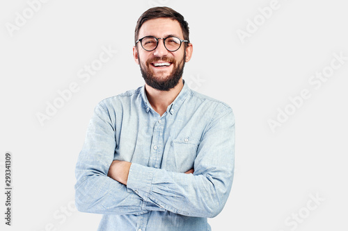 Friendly face portrait of an authentic caucasian bearded man with glasses of toothy smiling dressed casual against a white wall isolated