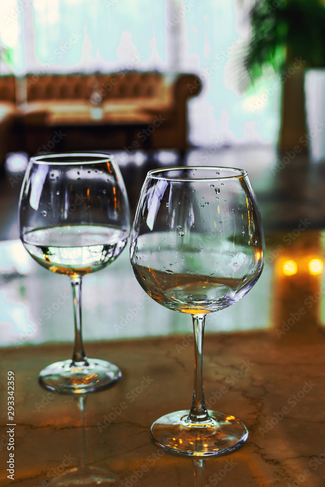 Obraz premium Two empty wine glasses on the hotel table. The reflection of the chandeliers, the conceptual event meeting wedding negotiations