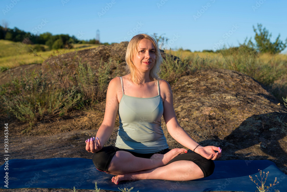 Young woman doing yoga exercises outdoors.