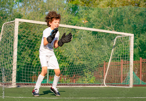 Summer soccer tournament for young kids. football club. emotions and joy of the game. Young goalie. Kids - soccer champion. Boy goalkeeper in football sportswear on stadium with ball. Sport concept.