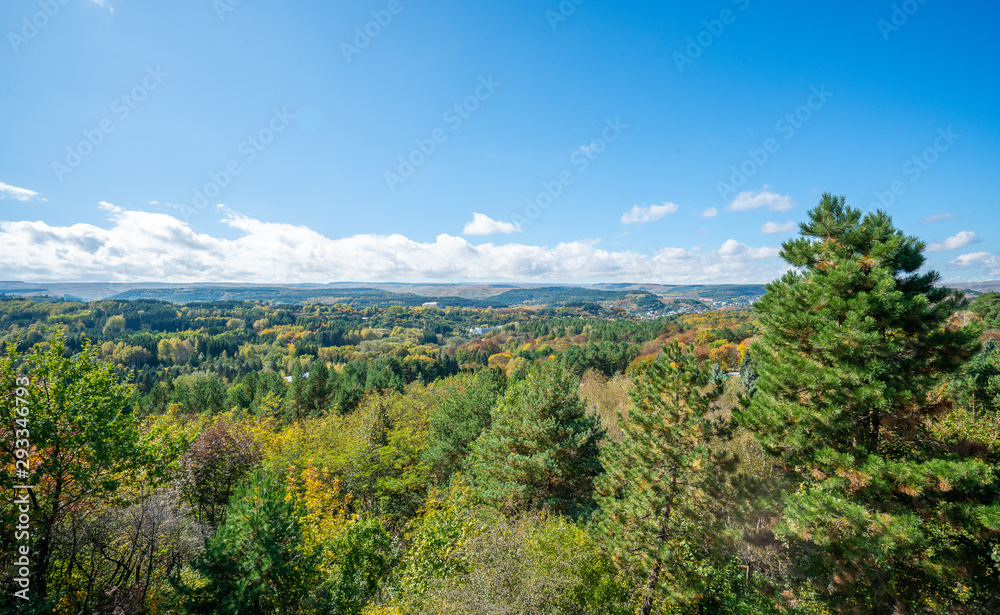 Kislovodsk resort park from above: tops of colorful trees, mountains and sky