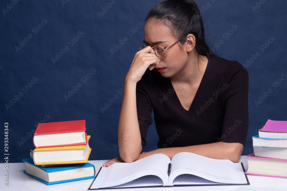 Exhausted Asian woman got headache read a book with books on table. Exhausted Asian woman got headache read a book with books on table.