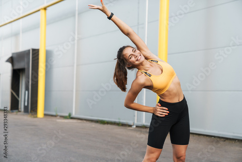 Fototapeta Naklejka Na Ścianę i Meble -  Image of joyful woman in sportswear smiling and doing workout outdoors