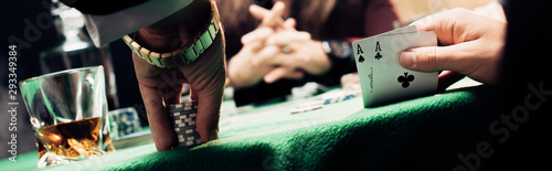 panoramic shot of man touching playing cards and poker chips near player photo