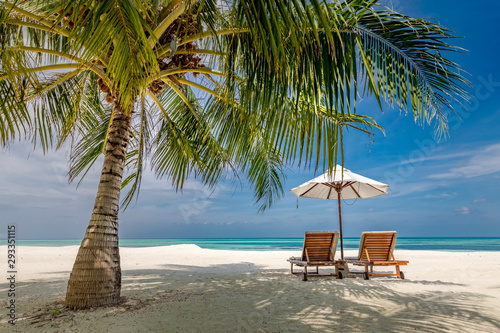 Beach landscape, chairs and umbrella next to palm tree on white sand. Peaceful tropical nature landscape. Calmness beach, luxury vacation and travel concept