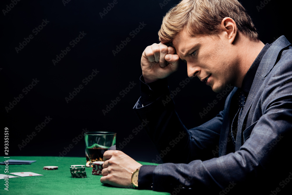 side view of frustrated man playing poker isolated on black side view of frustrated man playing poker isolated on black