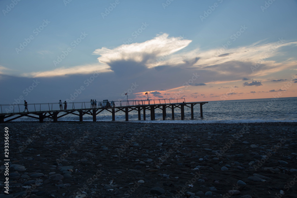 sun setting over Batumi beach pier, as powerful waves roll in, and a very colorful sky is reflected on the beach sun setting over Batumi beach pier, as powerful waves roll in, and a very colorful sky is reflected on the beach